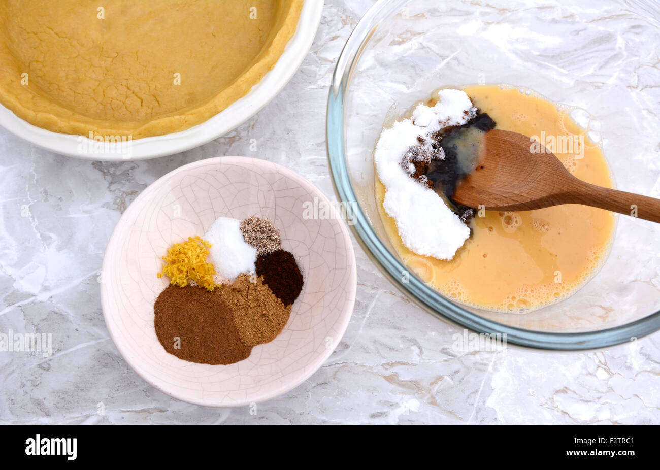 Ingredients for pumpkin pie filling - spices, sugars and egg - with pie shell Stock Photo