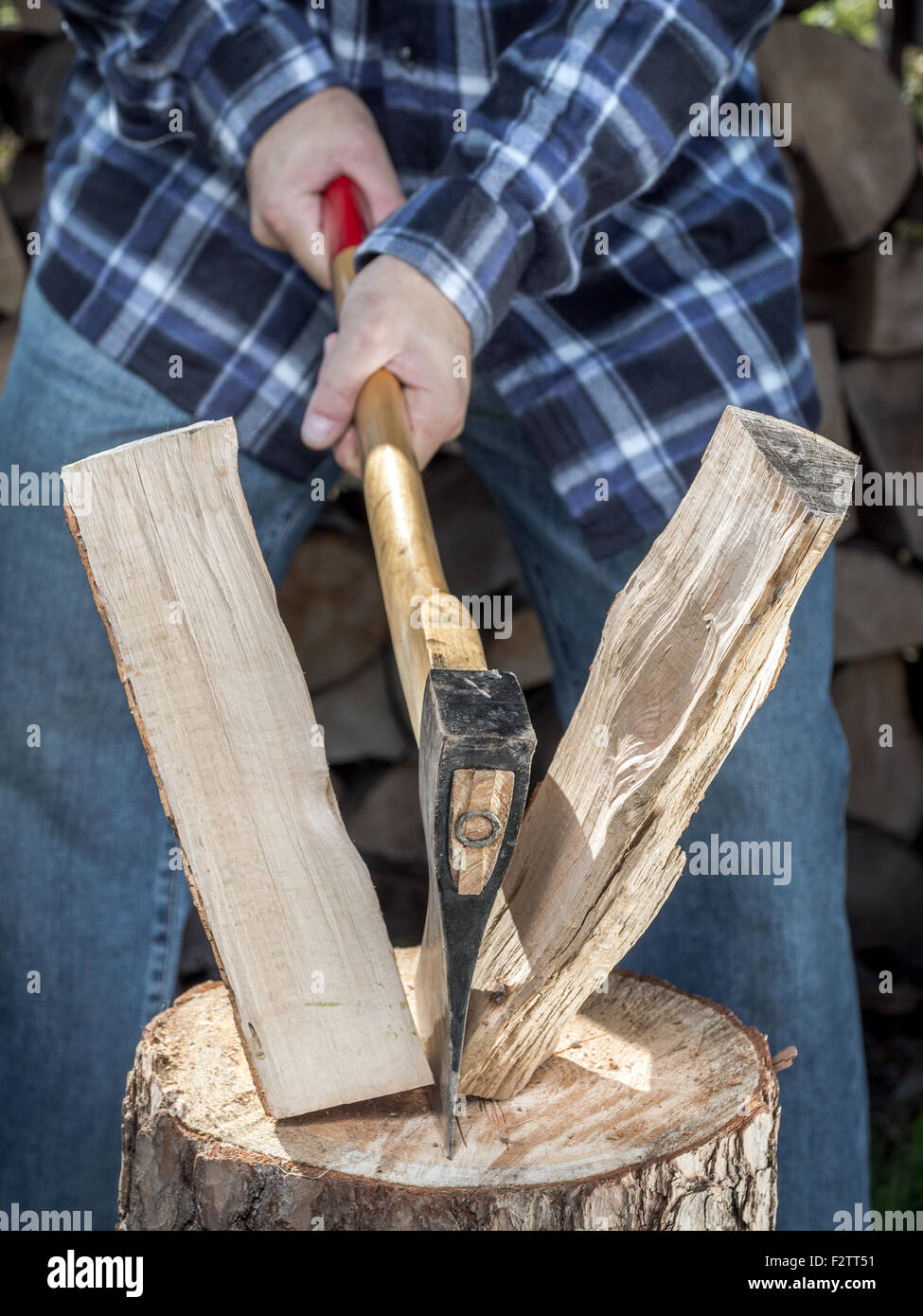 Man splitting log on chopping block with axe Stock Photo