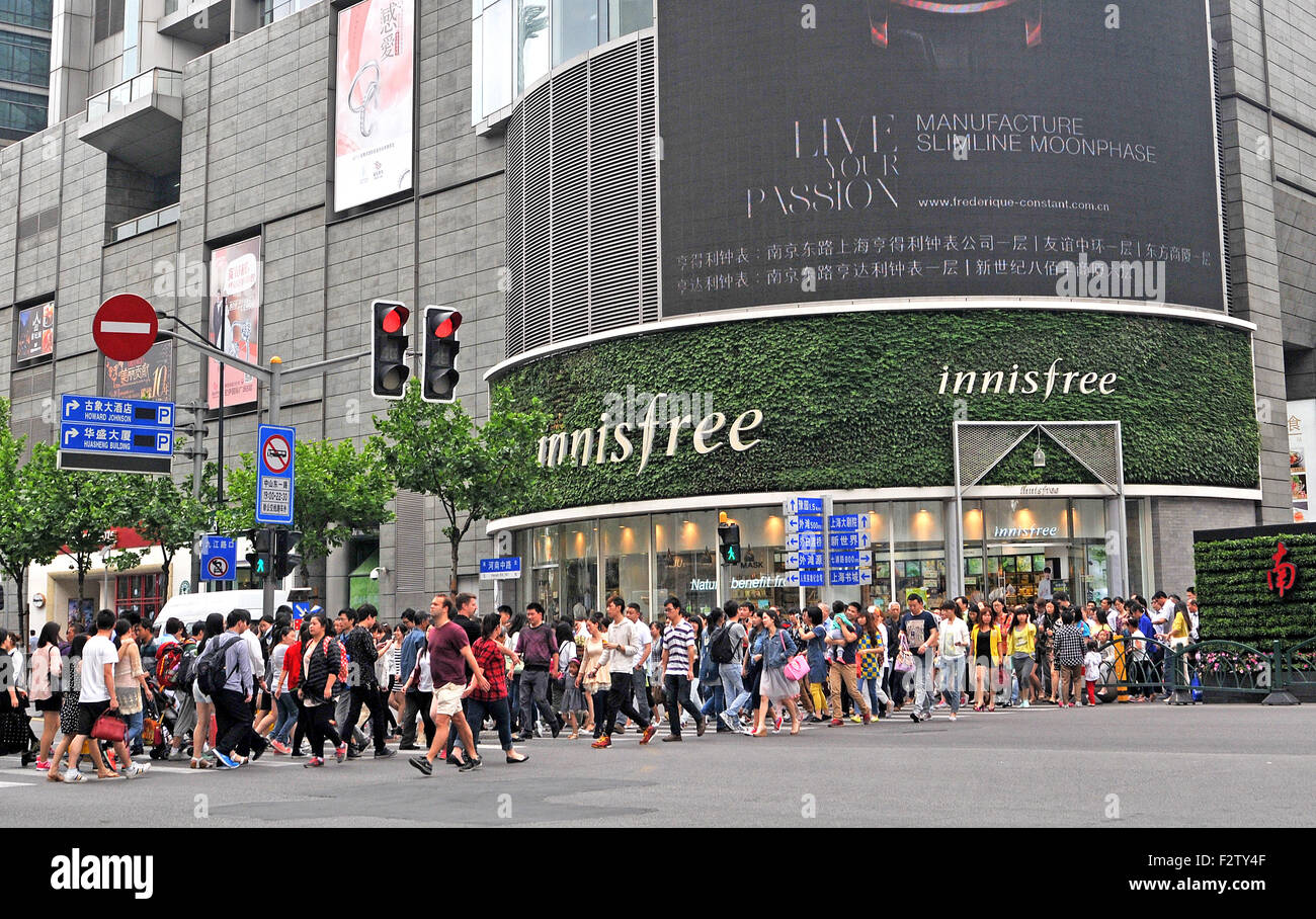 pedestrians crossing a main street, Innisfree boutique, Shanghai China Stock Photo