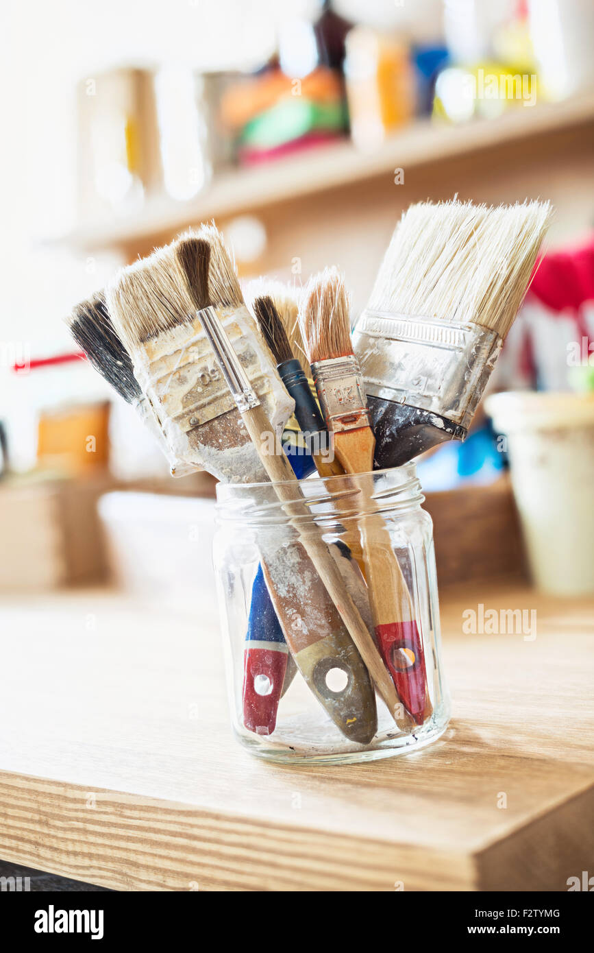 artist apron with paint brushes hanging on brick wall Stock Photo