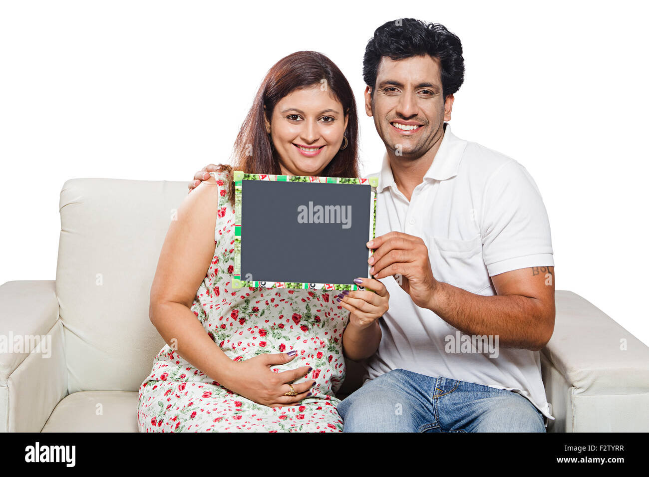 2 indian Married Couple Pregnant home sofa sitting Slate Board Showing Stock Photo