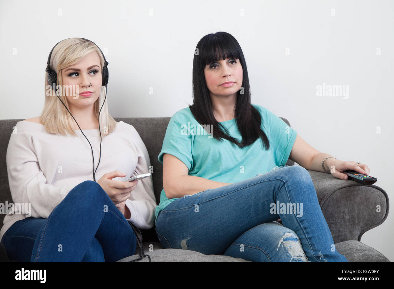 Mother and teenage daughter sitting on a sofa together. Stock Photo