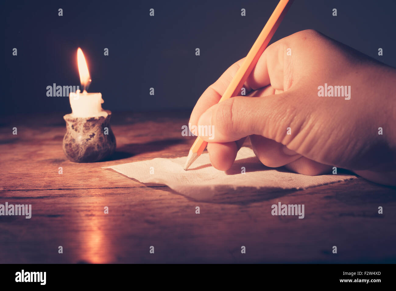 Closeup on a hand writing by candlelight Stock Photo