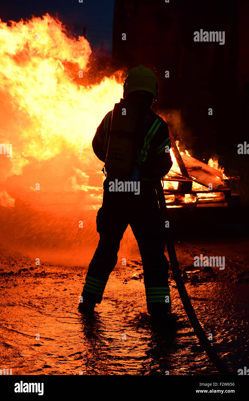 Firefighter in breathing apparatus extinguishes a fire Stock Photo