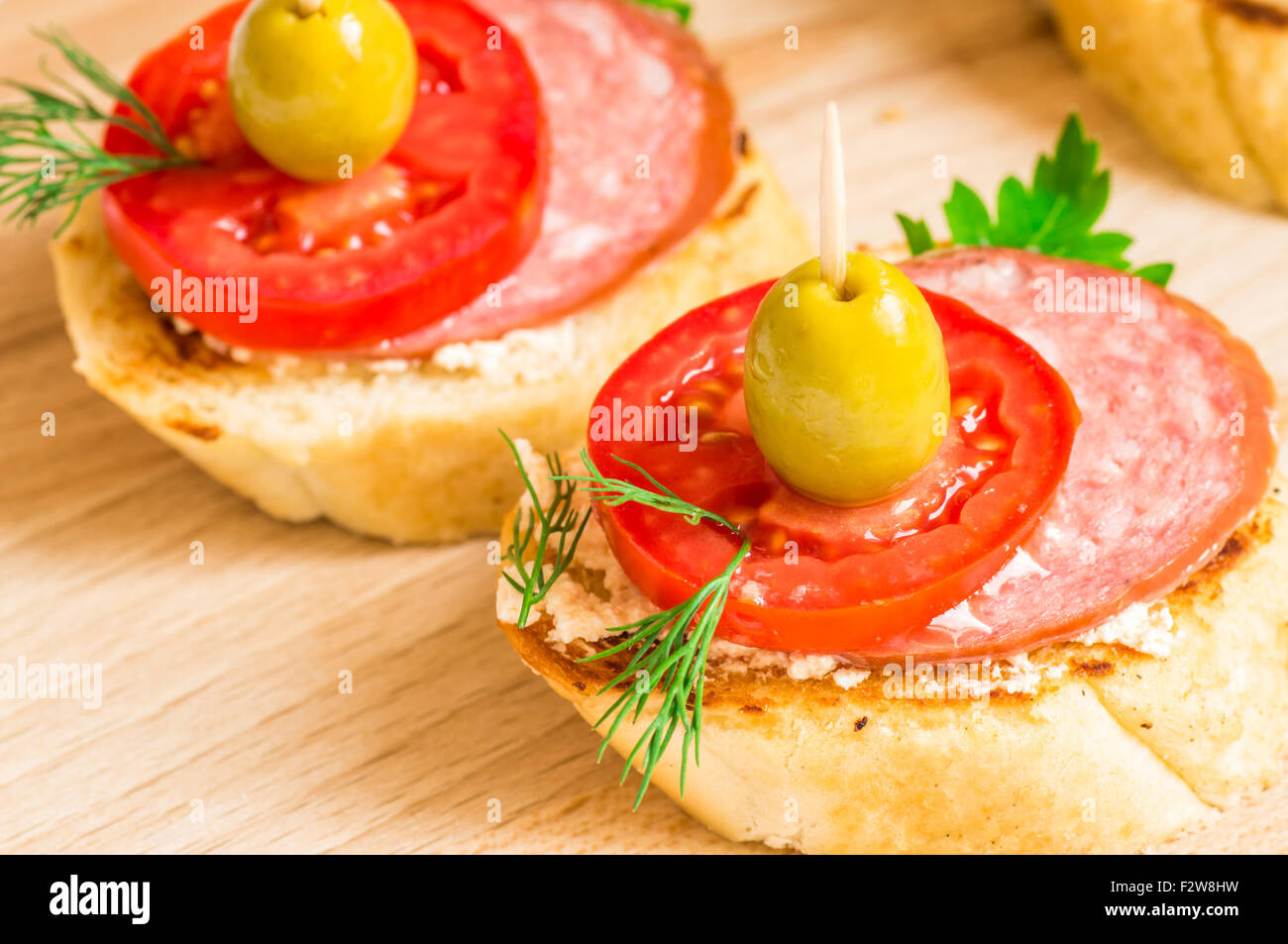 Tasty snack with salami cervelat, tomato and green olives Stock Photo