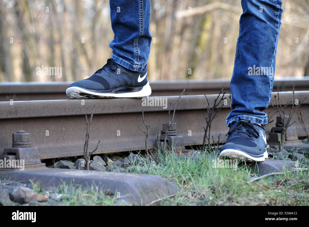 09.05.2015, Sandkrug, Lower Saxony, Germany - Teenager standing on a railroad track. 0HD150509D046CAROEX.JPG - NOT for SALE in Stock Photo