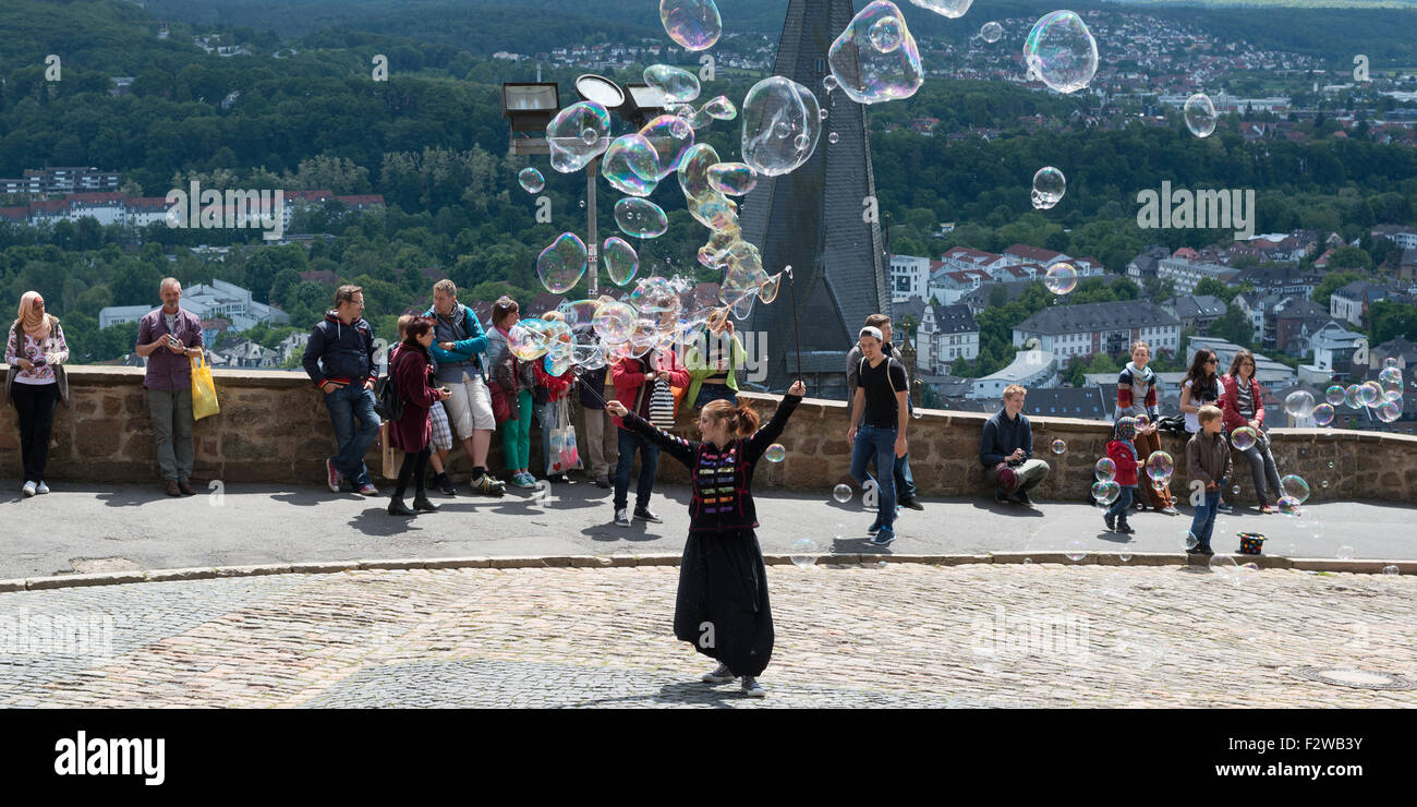 30.05.2015, Marburg, Hesse, Germany - Seifenblaeserin front of the castle of Marburg. The bubbles are caused by the wind Stock Photo
