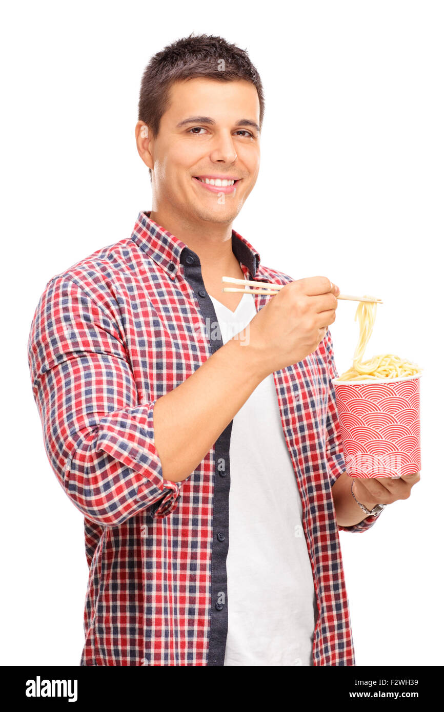 Vertical shot of a joyful young man eating Chinese noodles with sticks and looking at the camera isolated on white background Stock Photo