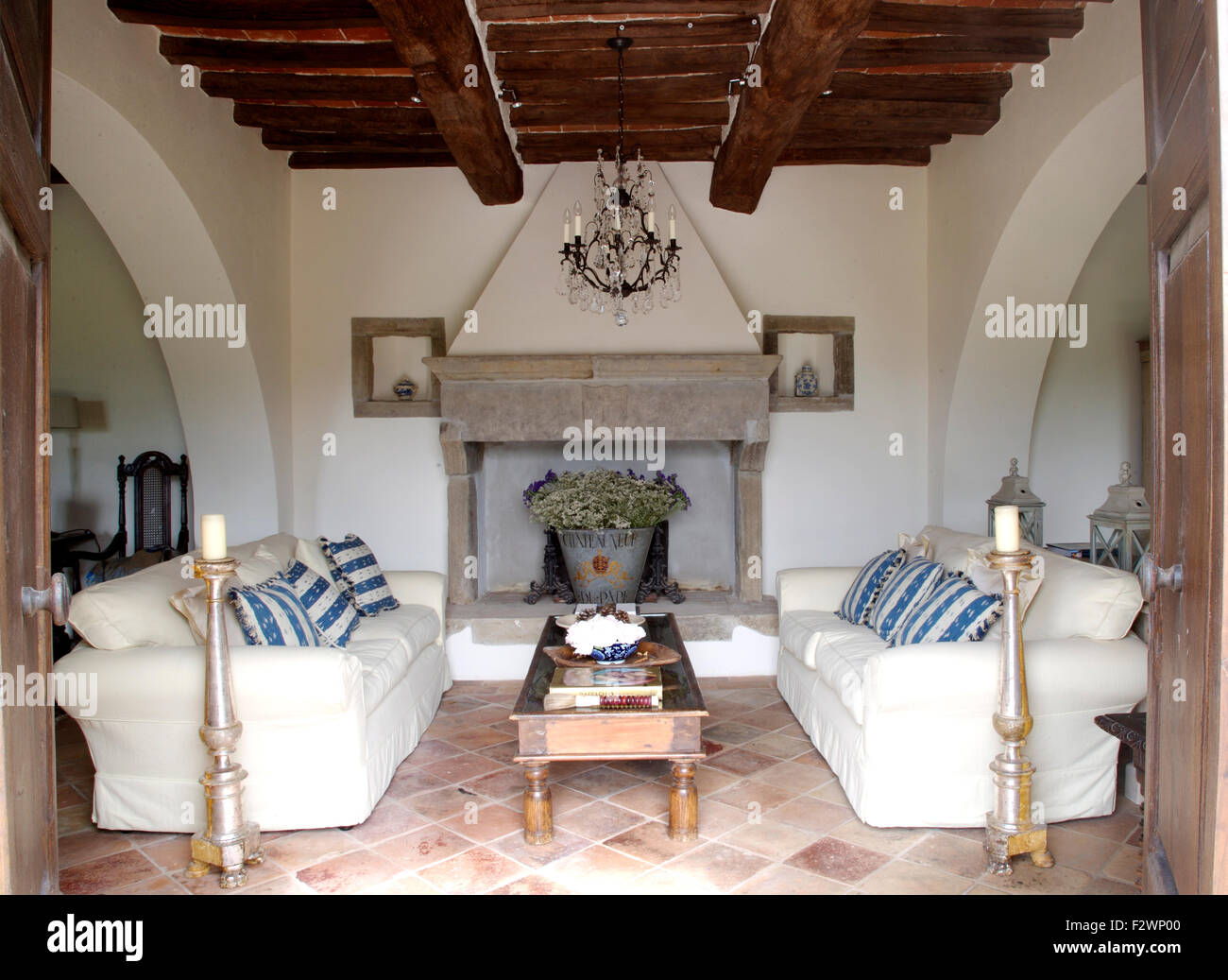 Tall brass candlesticks and white sofas either side of coffee table and