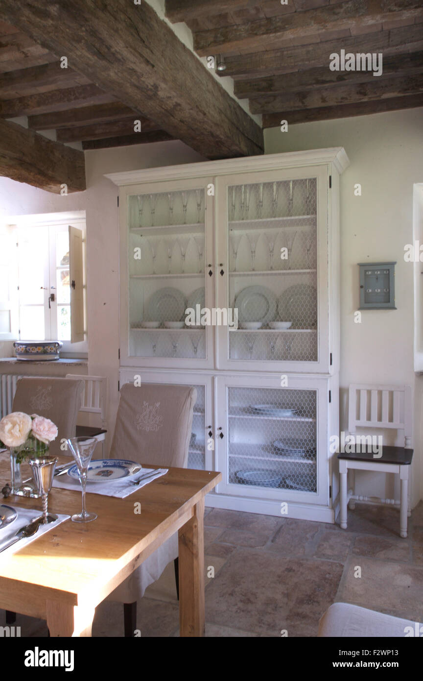 Glassware and white crockery in painted glass front dresser in Italian country dining room Stock Photo