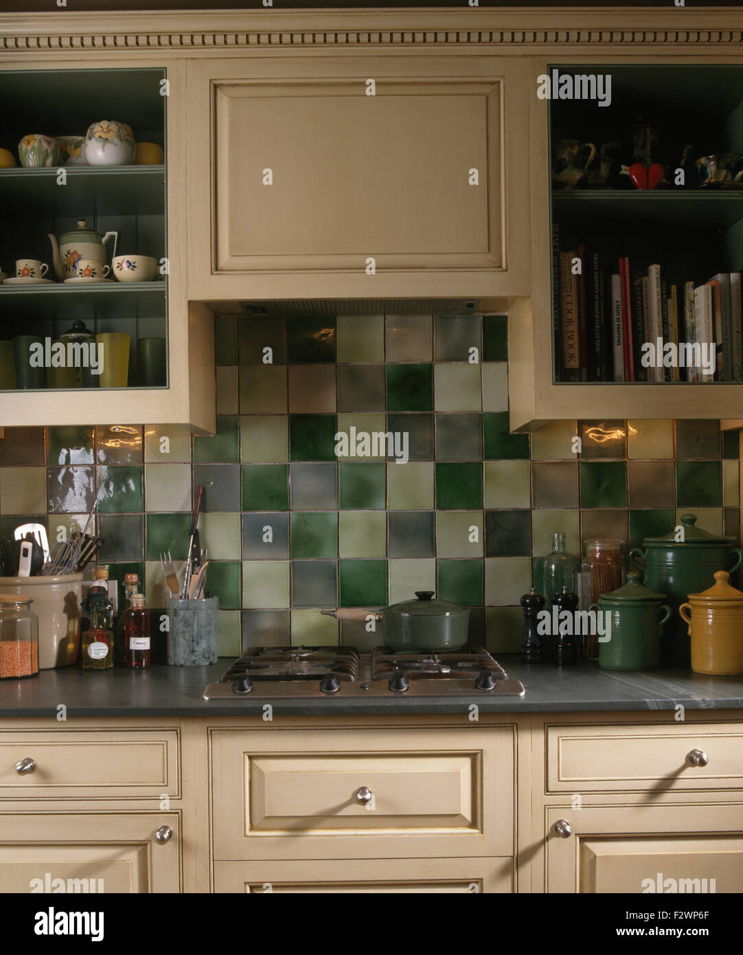 Green tiled splash back above worktop with fitted hob in nineties kitchen Stock Photo