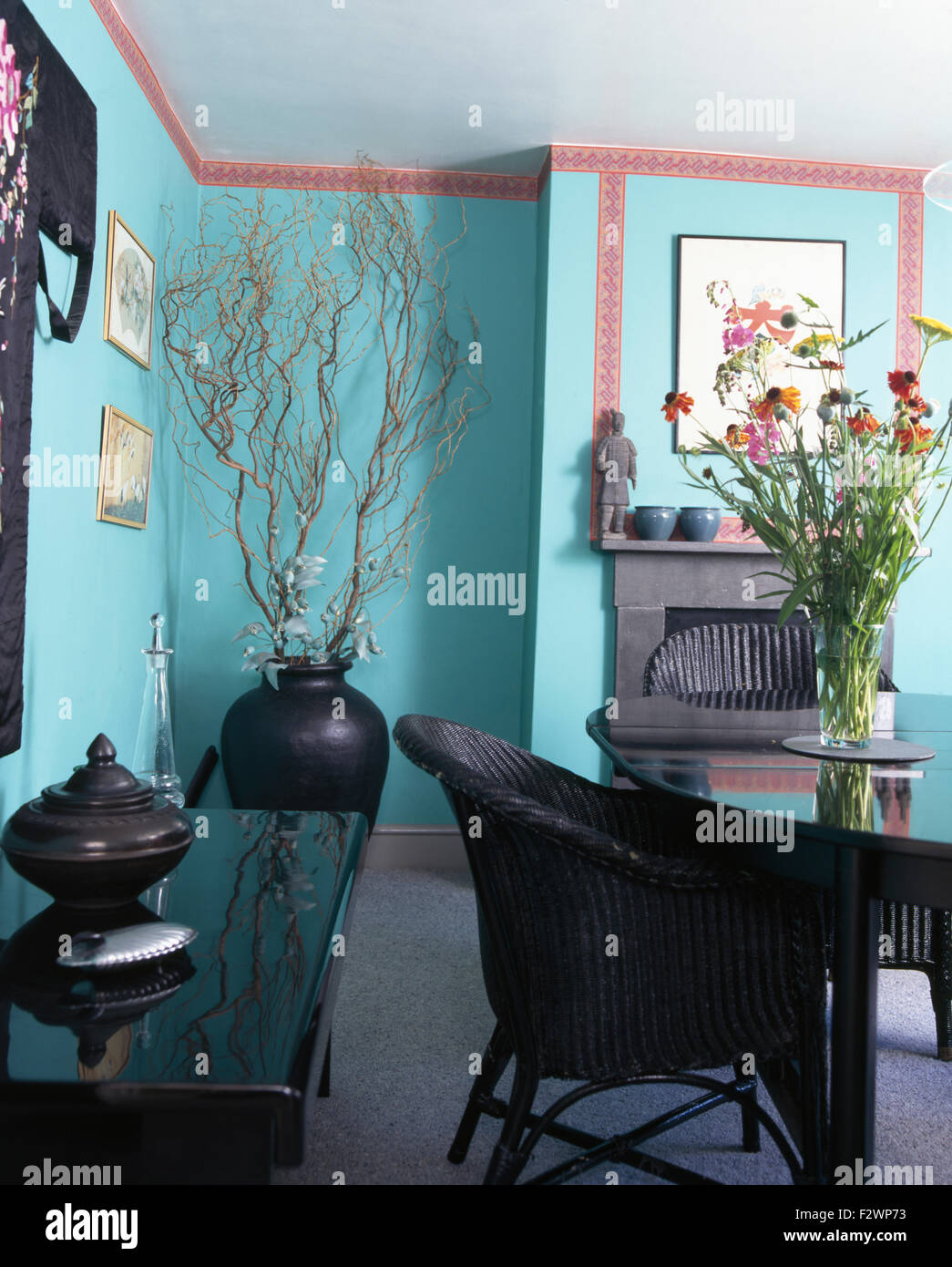 Black wicker chairs at table in turquoise nineties dining room Stock Photo