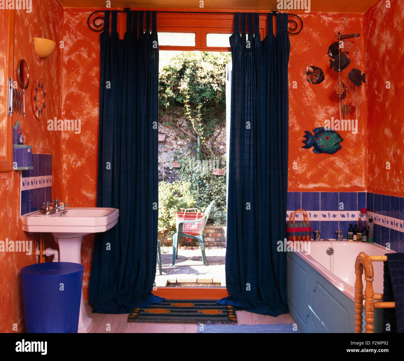 Blue Drapes On Open French Window In Orange Nineties Bathroom With