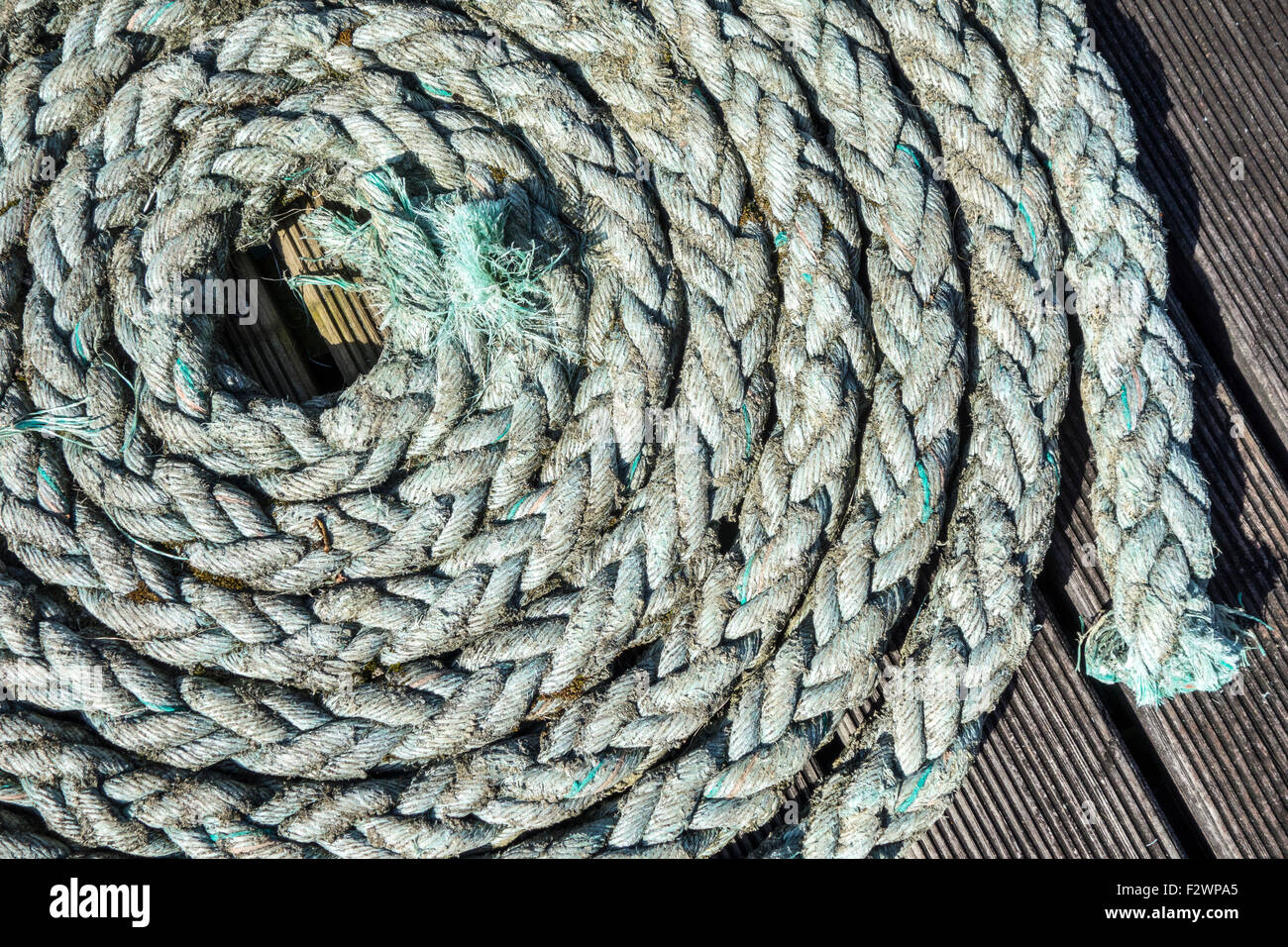 Close up of coiled braided rope / plaited hawser on deck of boat Stock Photo