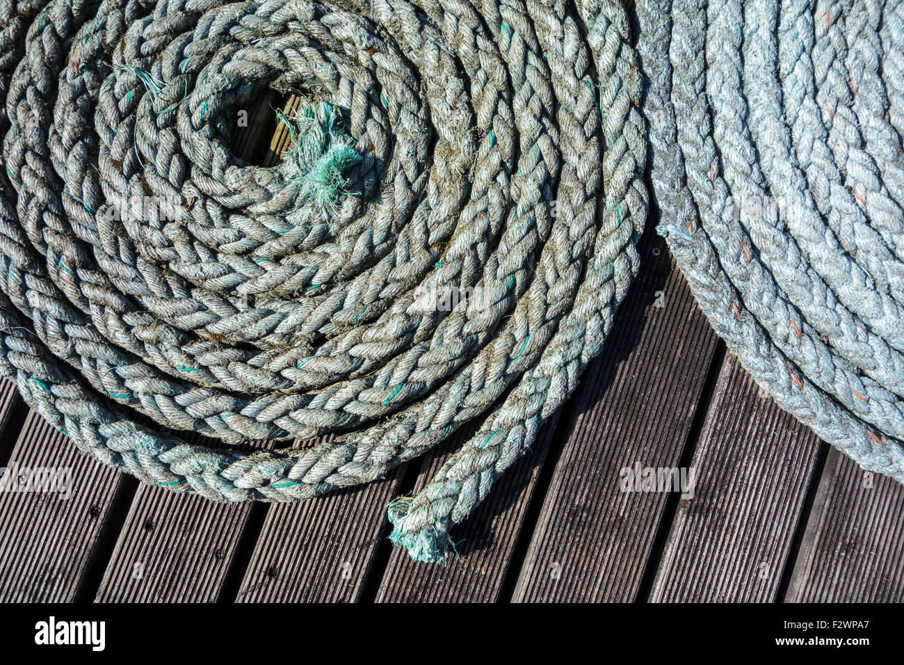 Close up of two coiled braided ropes / plaited hawsers on deck of boat Stock Photo
