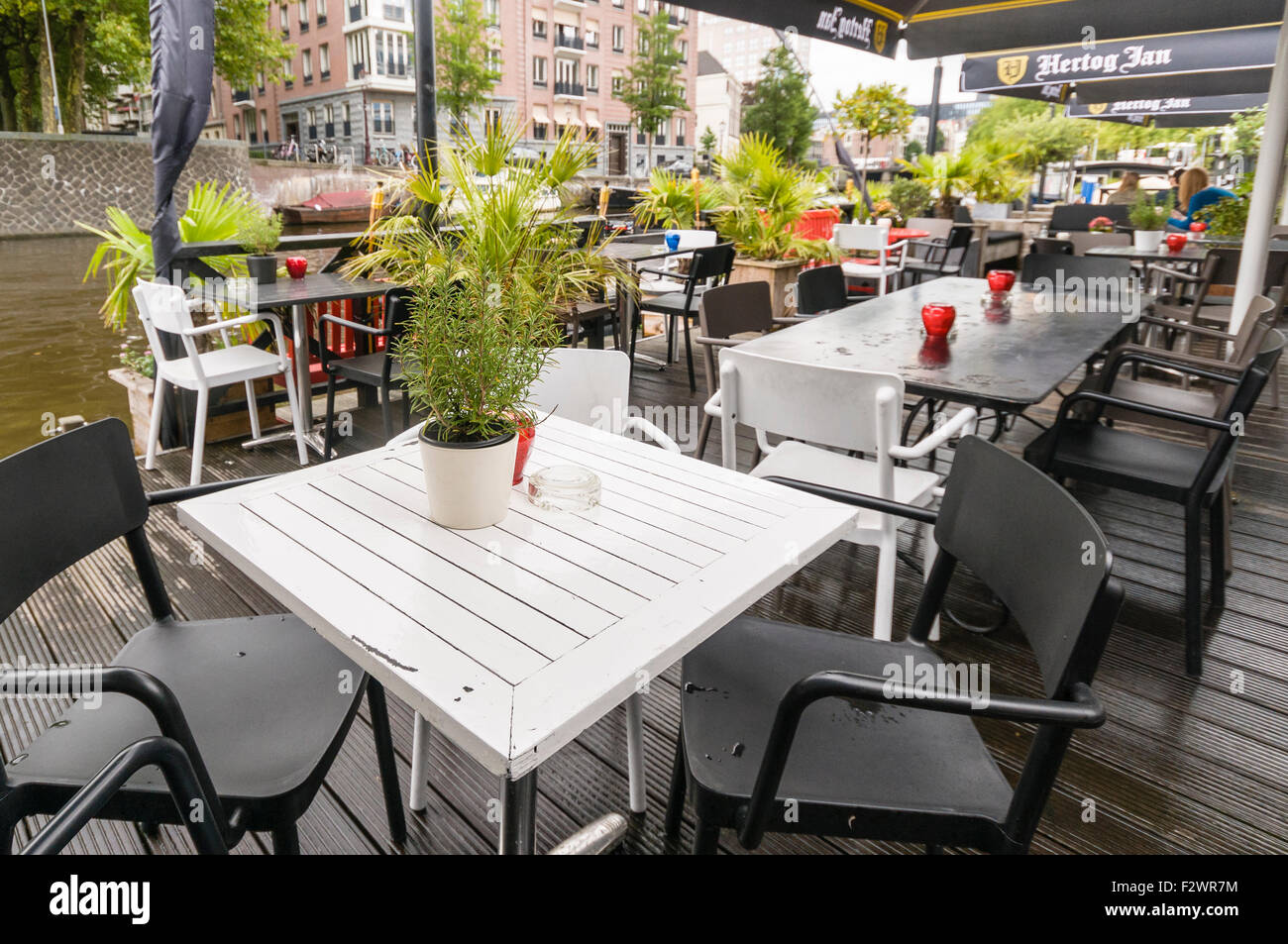 Dining tables on a veranda outside a bar in Amsterdam beside a canal. Stock Photo