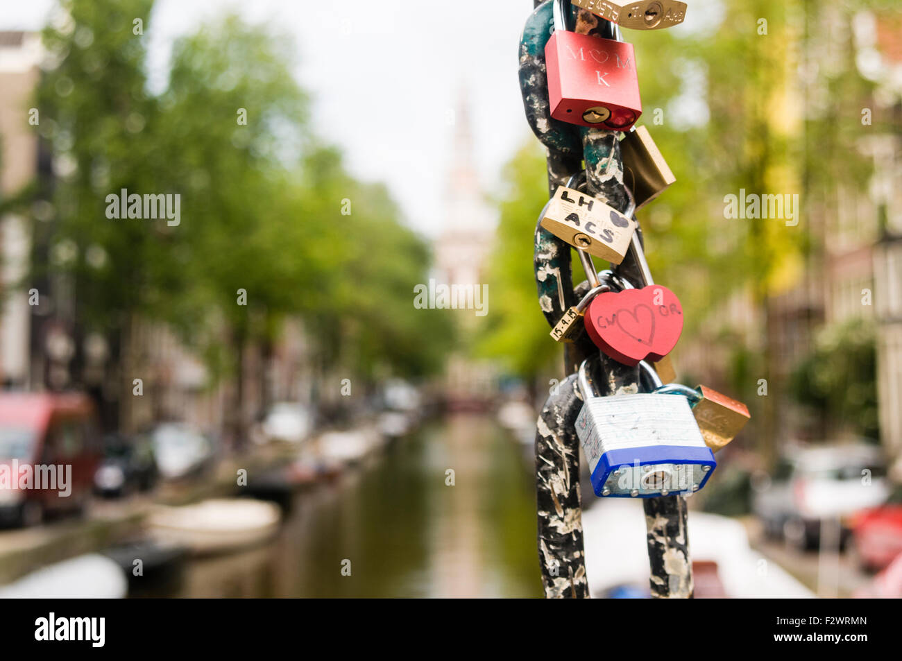 Padlocks attached to the chain of a bridge over a canal in Amsterdam