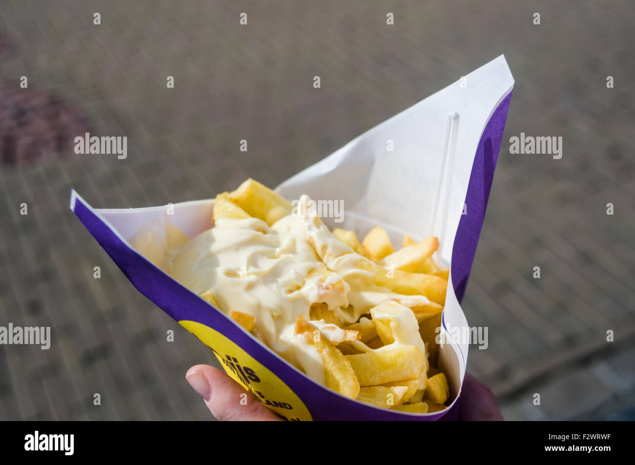 Woman holds a cone of chips fries with mayonnaise in Holland Stock