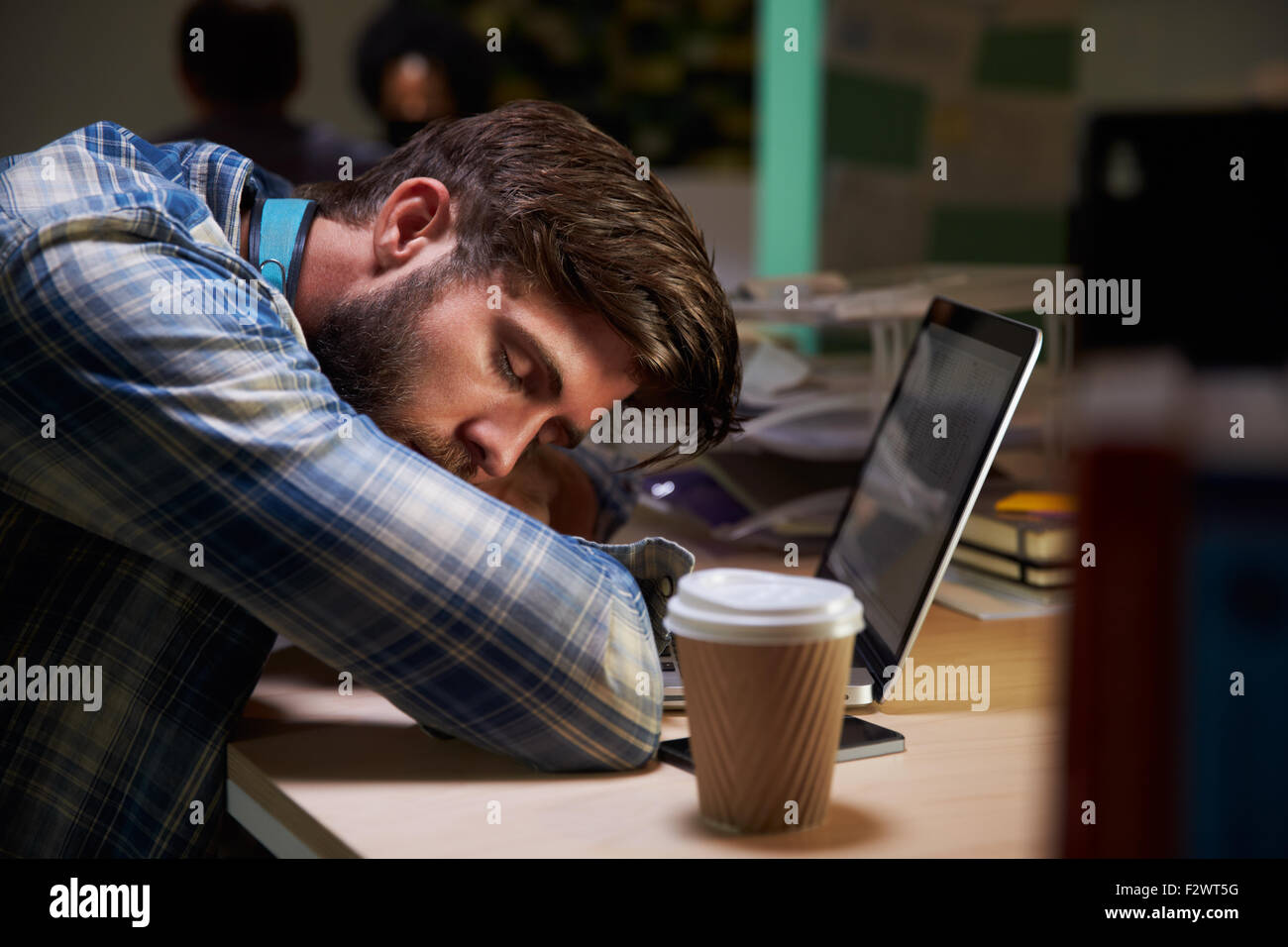 Male Office Worker Asleep At Desk Working Late On Laptop Stock Photo