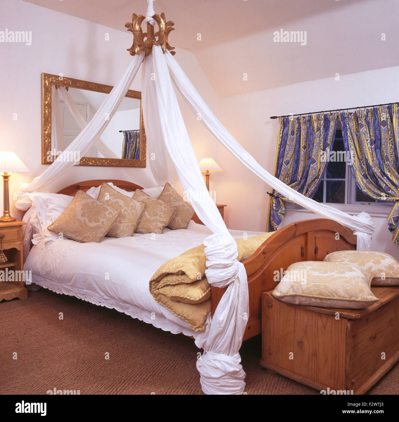 with white cotton drapes above pine bed in bedroom