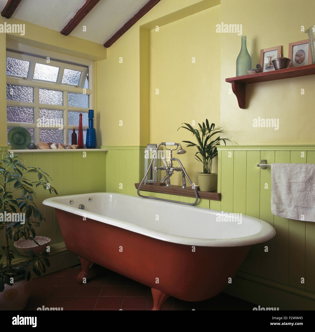 Roll top bath in nineties bathroom with frosted glass window and lime green tongue+groove dado panelling Stock Photo