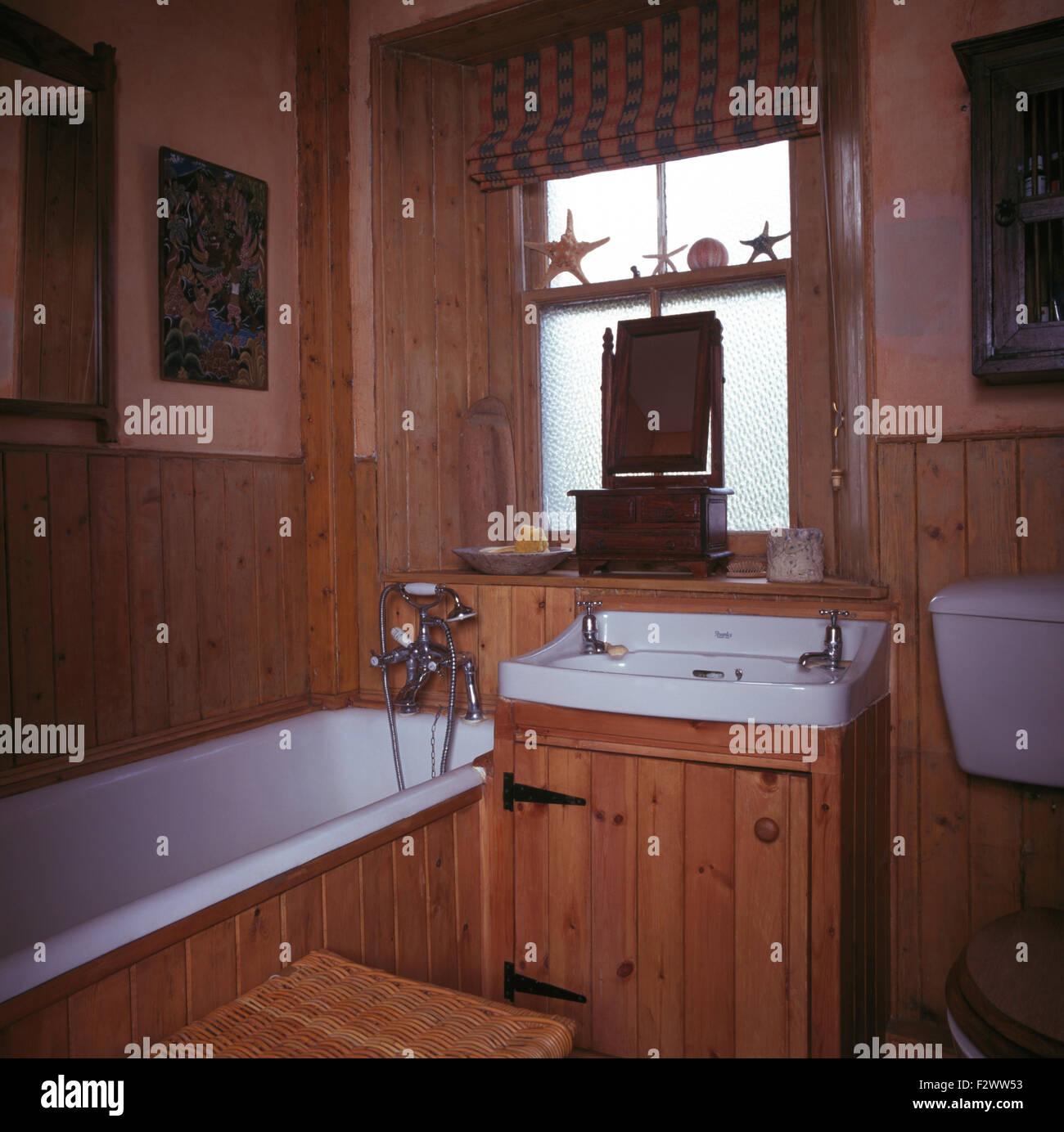 Blind on frosted window above basin in pine vanity unit in pine panelled nineties bathroom Stock Photo