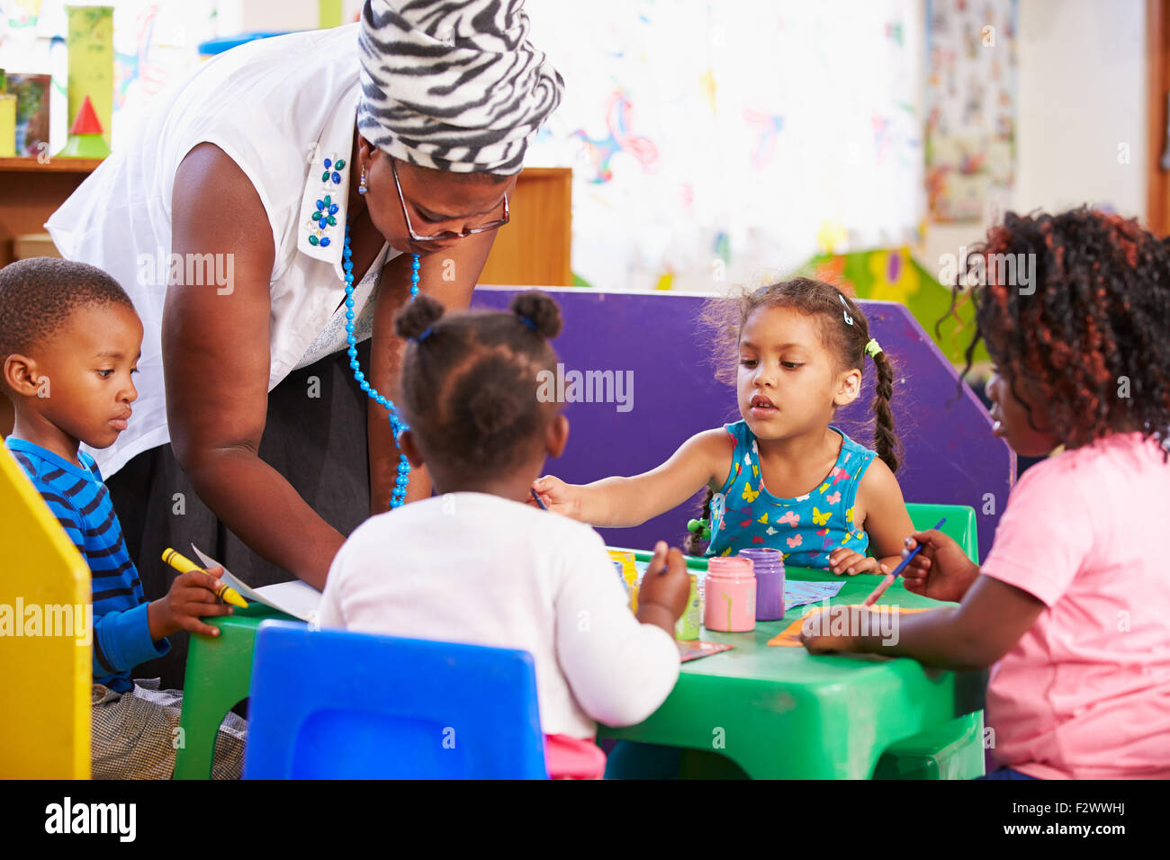 Teacher helping kids in a preschool class Stock Photo