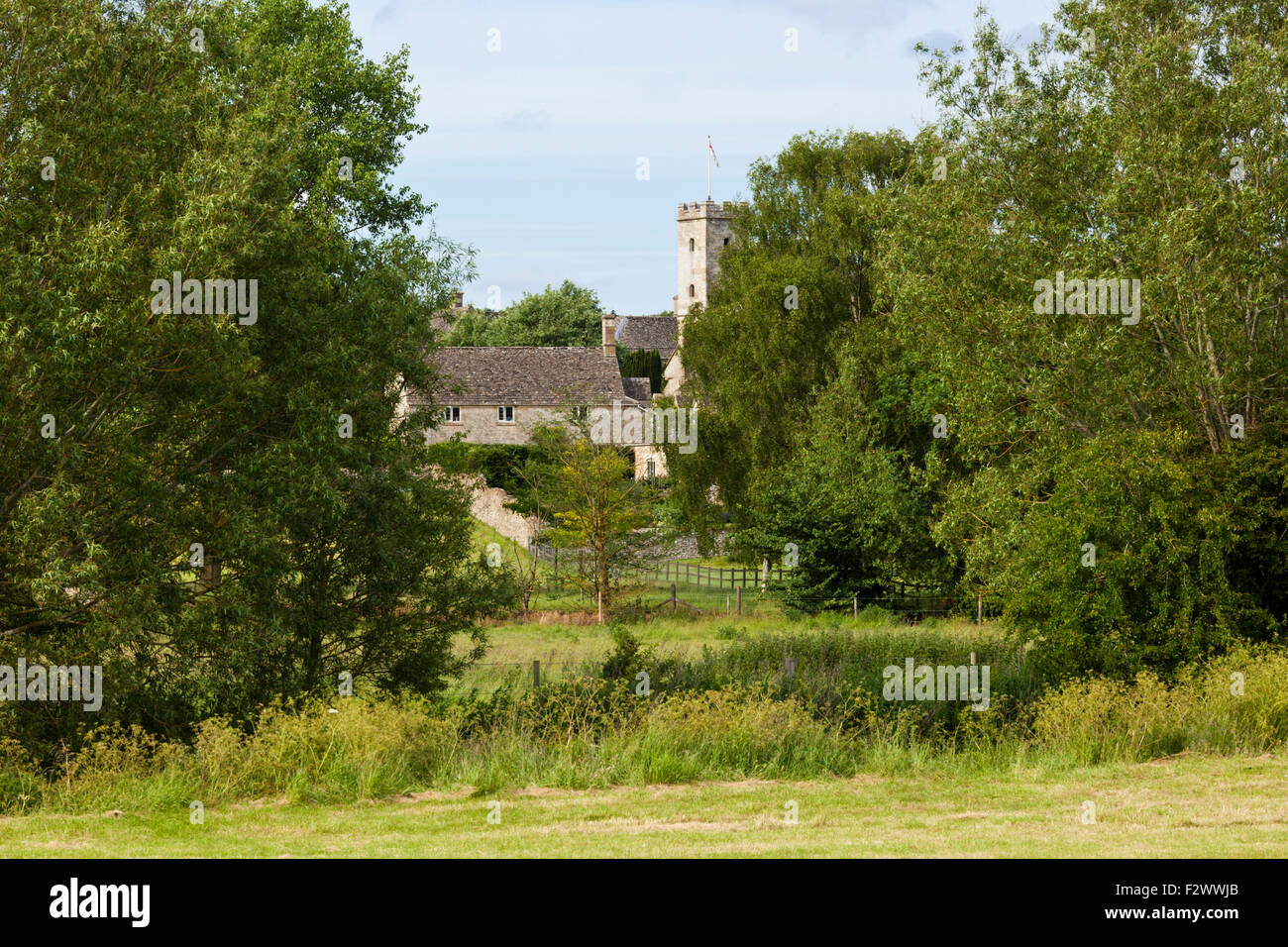 A glimpse of the Cotswold village of Swinbrook, Oxfordshire UK beside the River Windrush Stock Photo