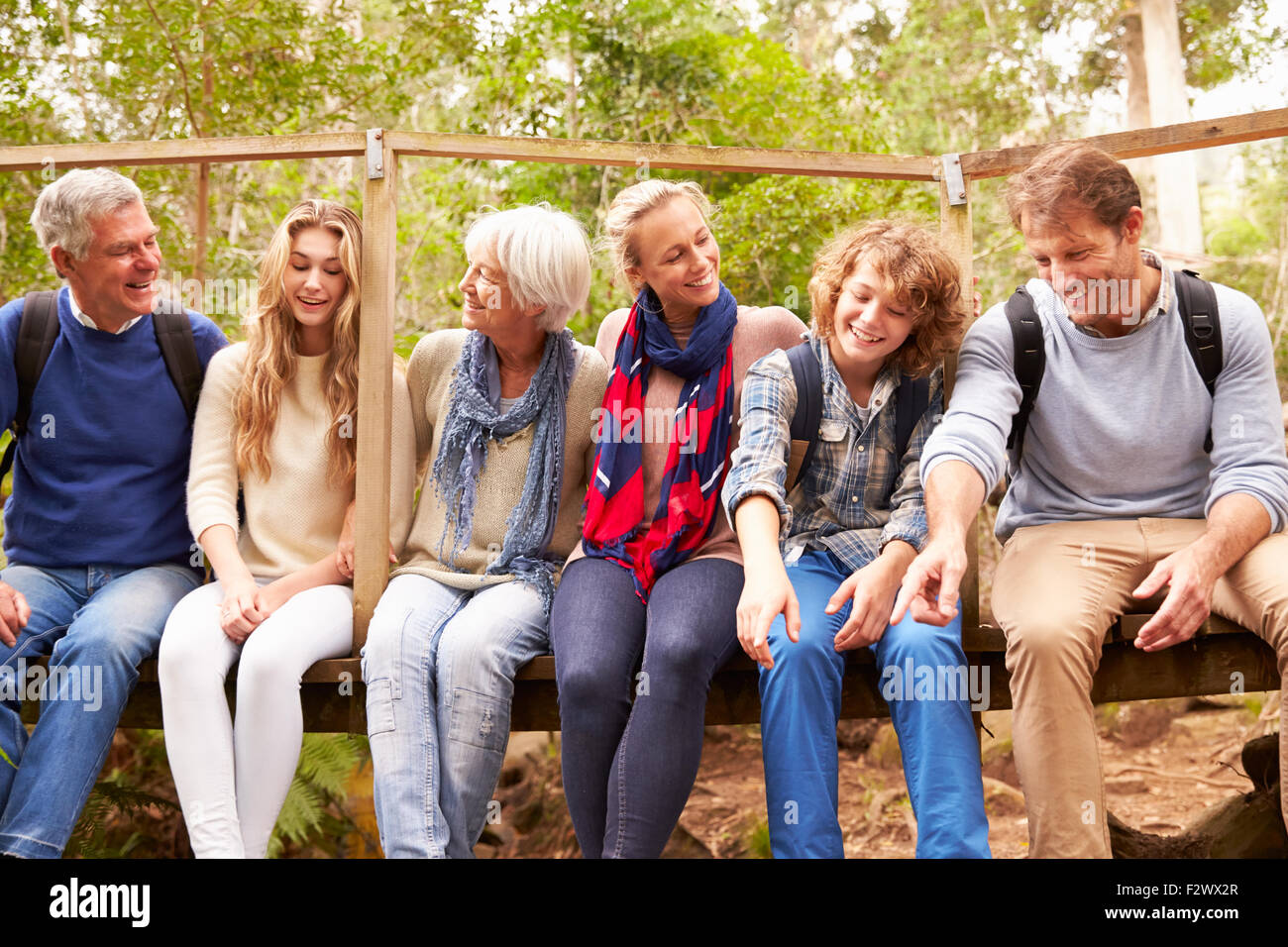 Family group sitting on a small bridge in a forest Stock Photo - Alamy