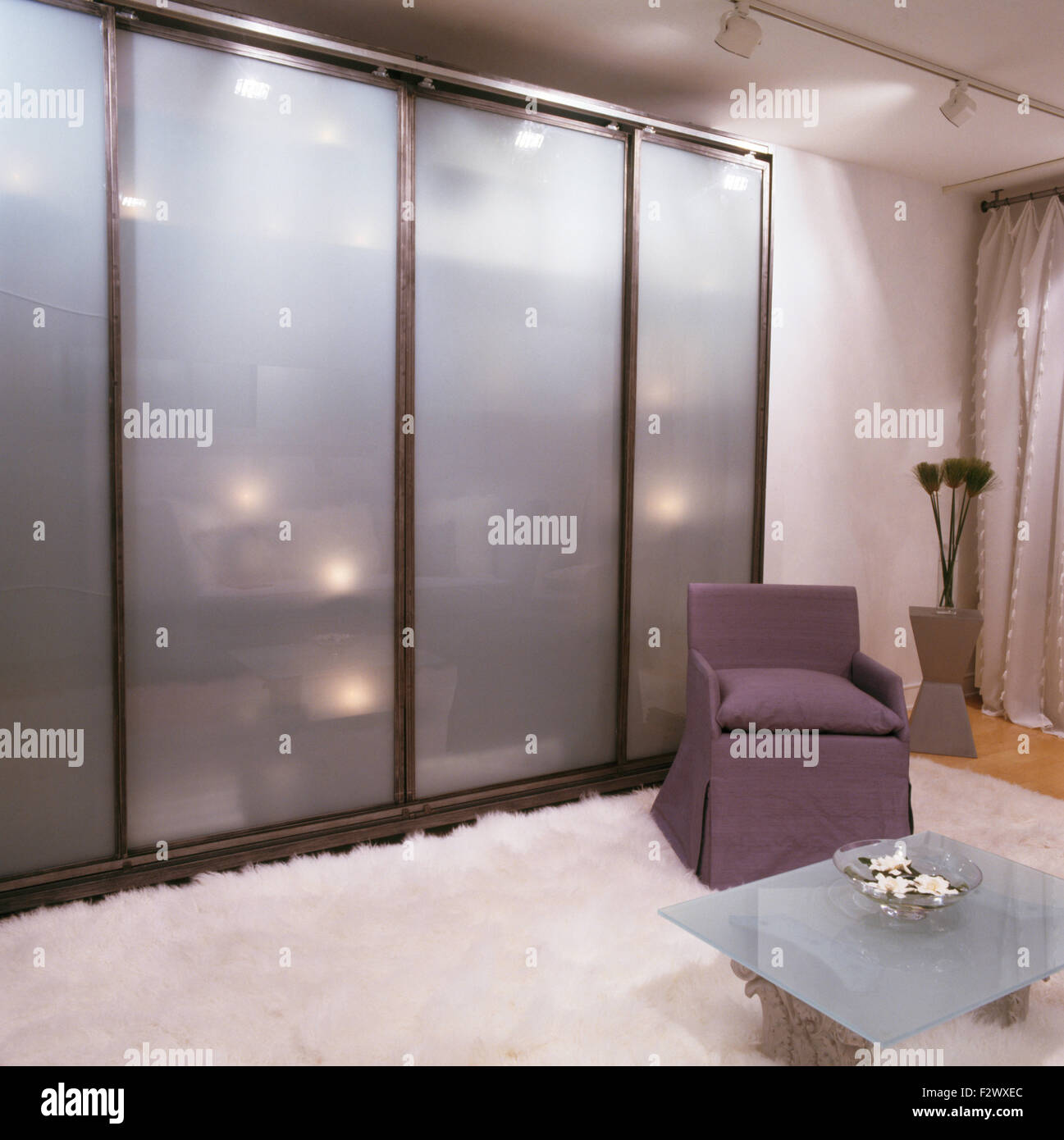 Opaque glass sliding doors on wardrobe in retro city bedroom with white fur rug on the floor Stock Photo