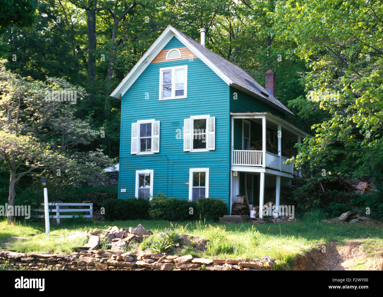 Exterior of turquoise painted three storey clapboard house with balcony
