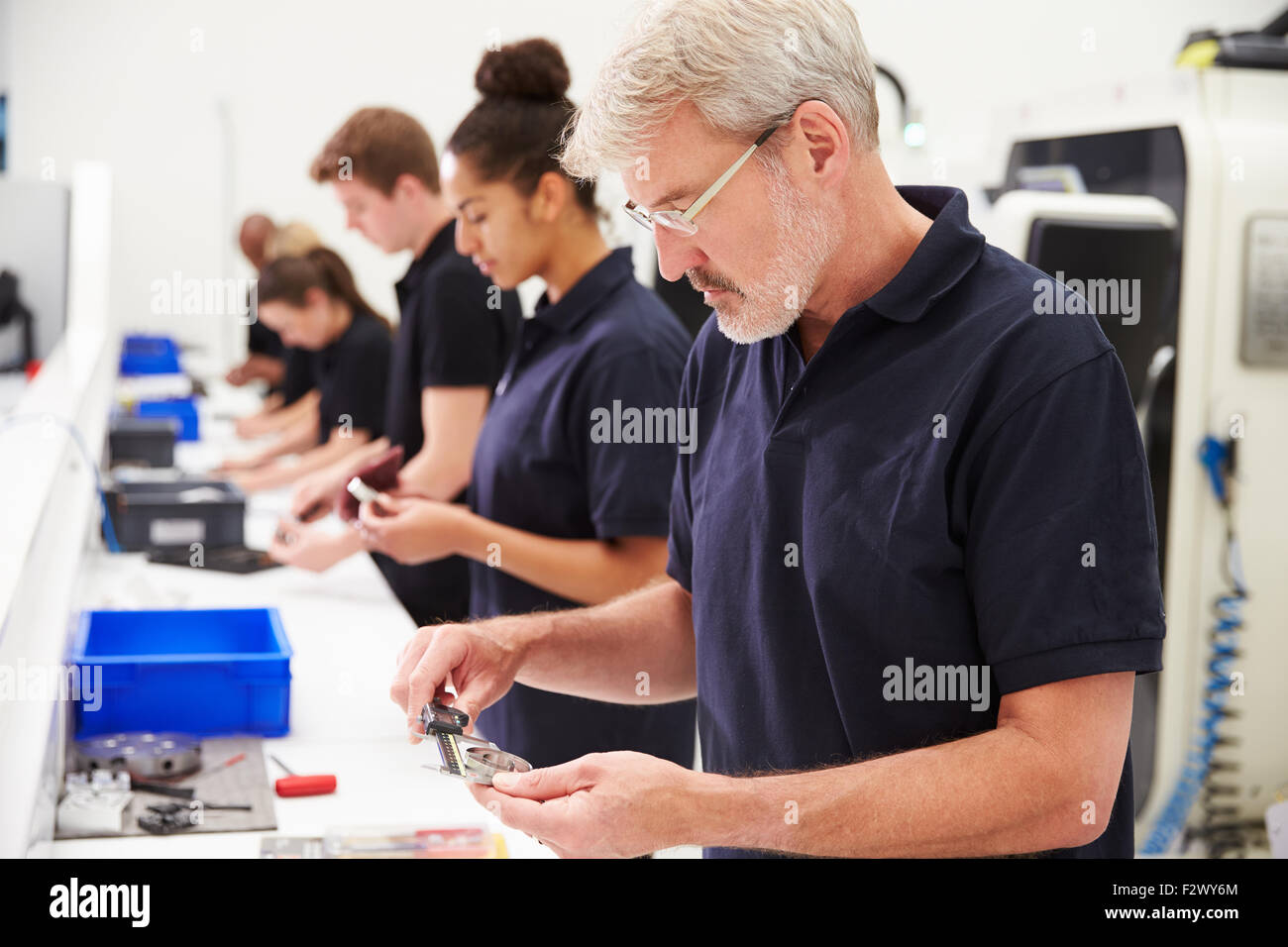 Workers In Engineering Factory Checking Component Quality Stock Photo