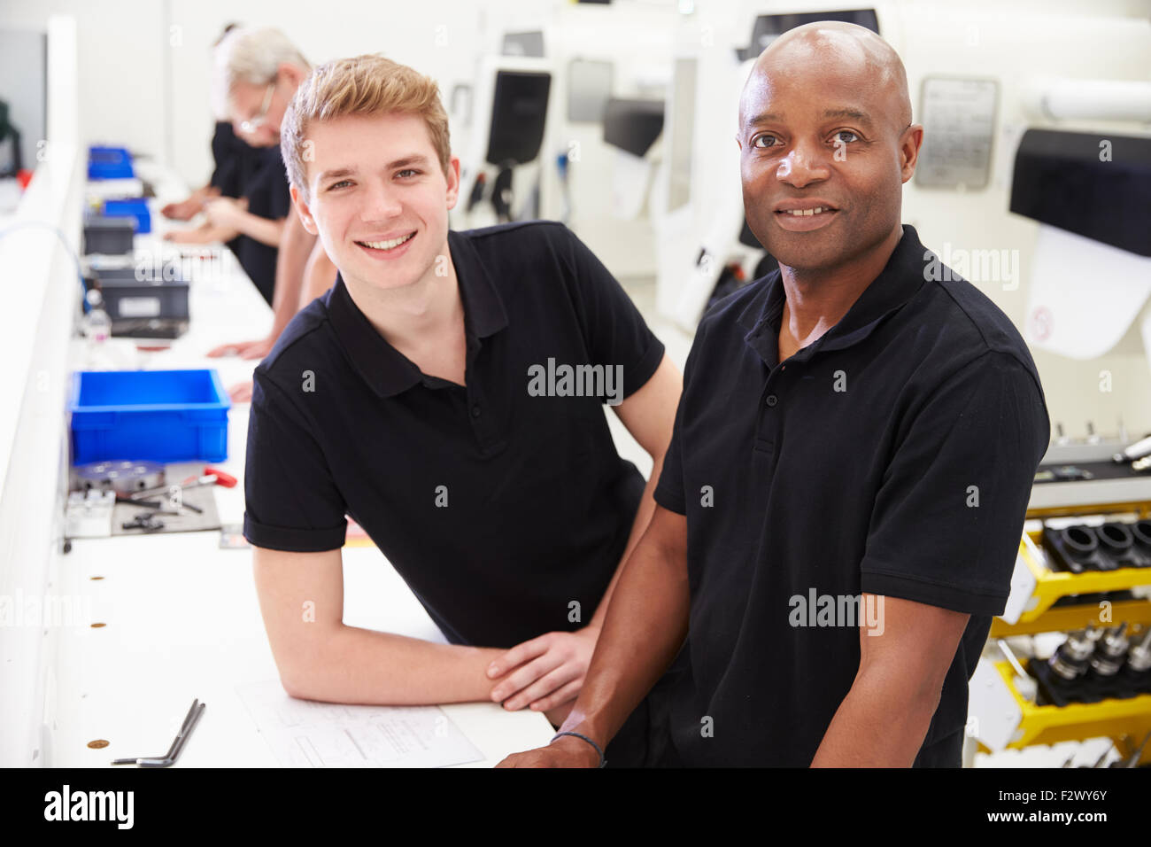 Portrait Of Engineer In Factory With Apprentice At Bench Stock Photo ...
