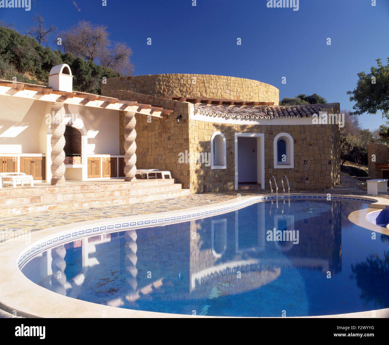 Curved swimming pool in front of single storey Spanish villa Stock Photo