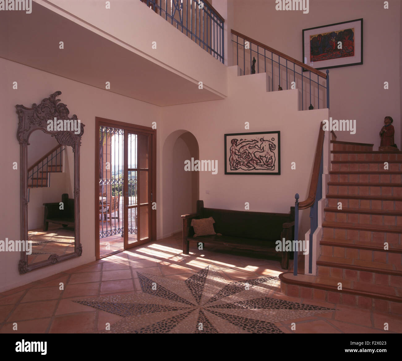 Wooden bench in Spanish villa hall with mosaic patterned floor and a