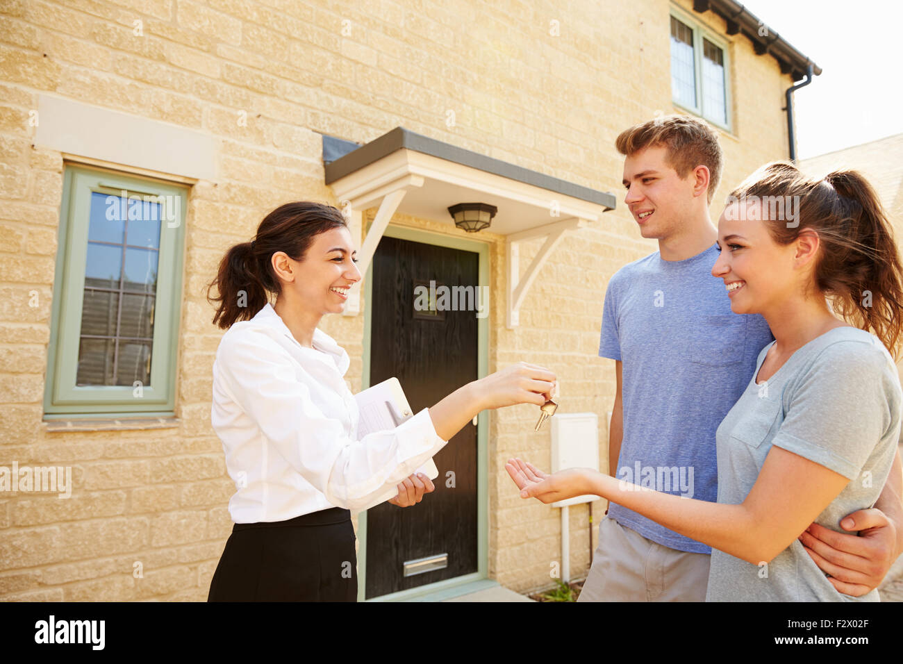 Female real estate agent giving keys to new property owners Stock Photo ...