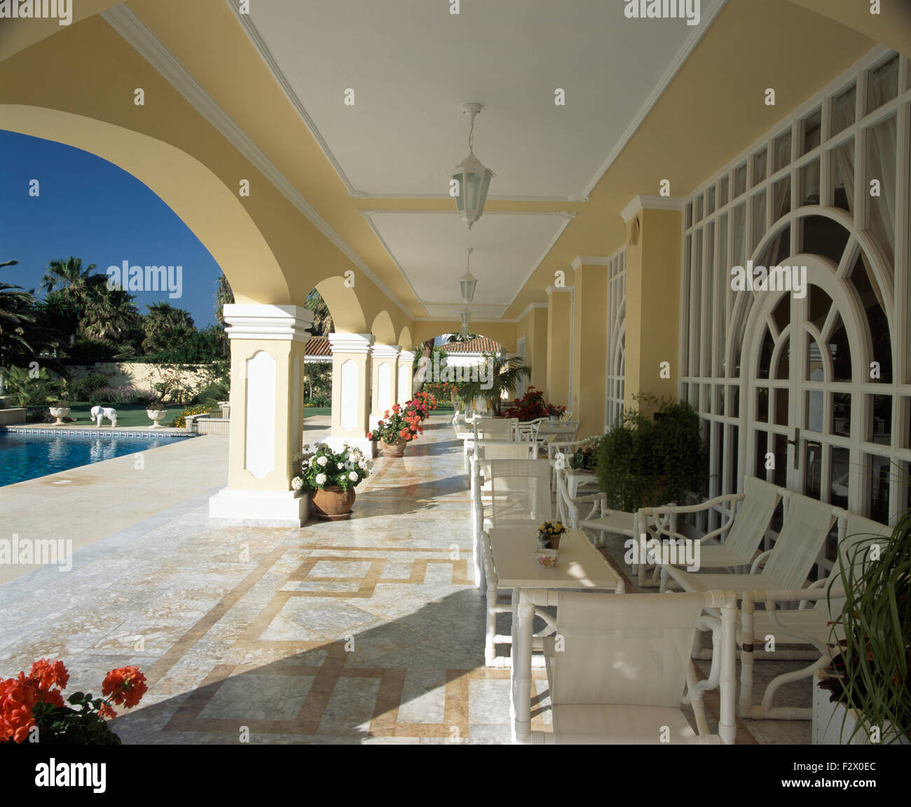White chairs and tables on long veranda of large Spanish villa Stock