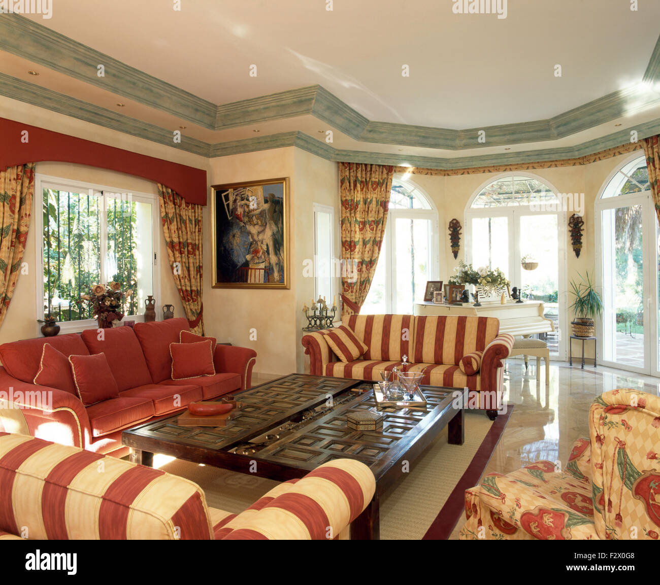 Red striped sofas set around carved wood coffee table in living room in  large Spanish villa Stock Photo - Alamy