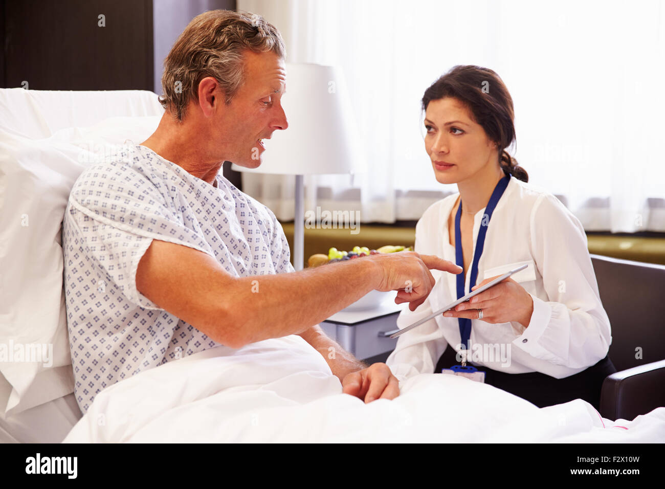 Female Doctor Talking To Male Patient In Hospital Bed Stock Photo - Alamy