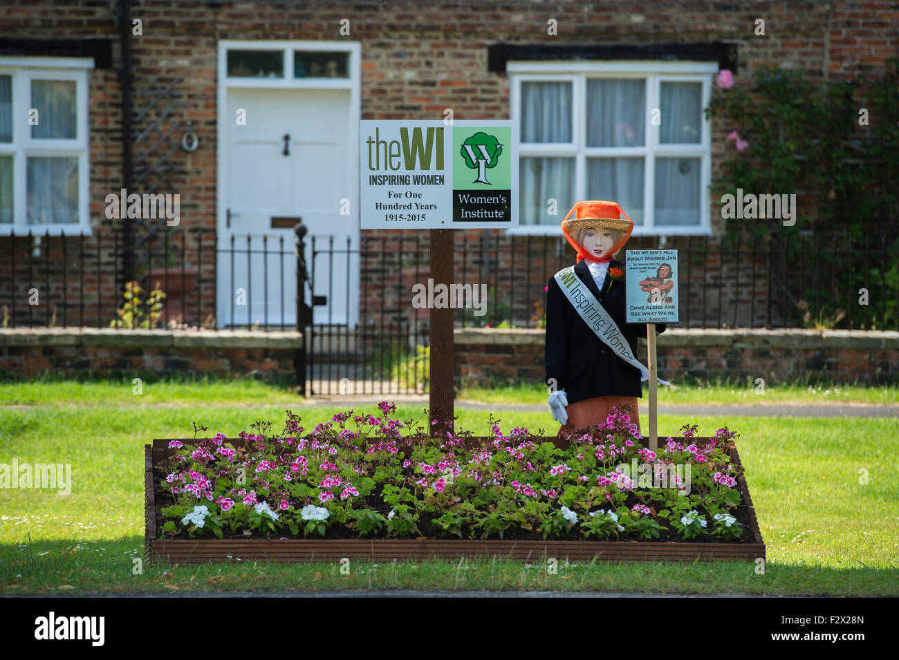 A scarecrow & floral display (raised bed of flowers) commemorate the centenary of The Women’s Institute (WI) - Upper Poppleton village, England, UK. Stock Photo