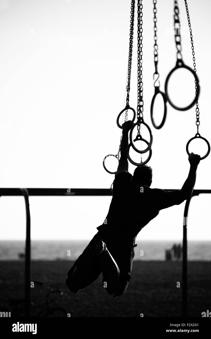 Silhouette of a person swinging on rings on the beach, Santa Monica ...