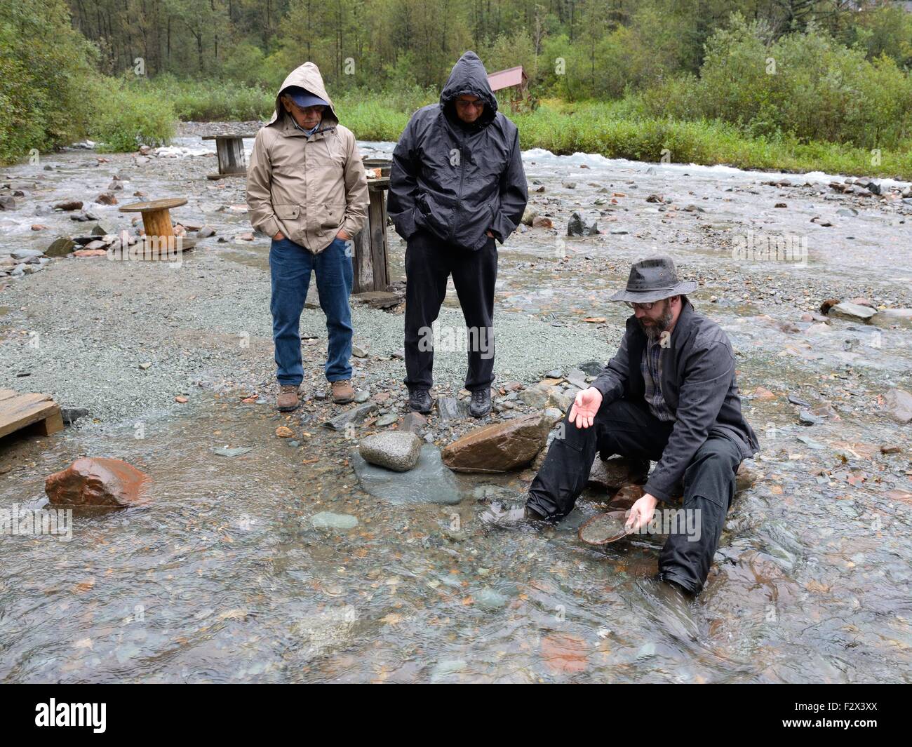 Guide showing tourists the techniques in panning for gold in a river