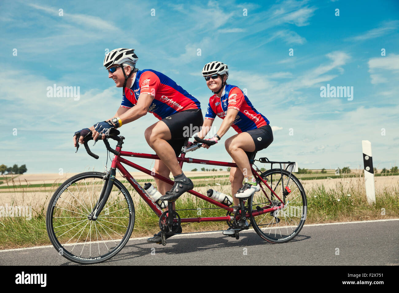 Germany, Rhineland-Palatinate, US American couple riding their tandem on a road Stock Photo