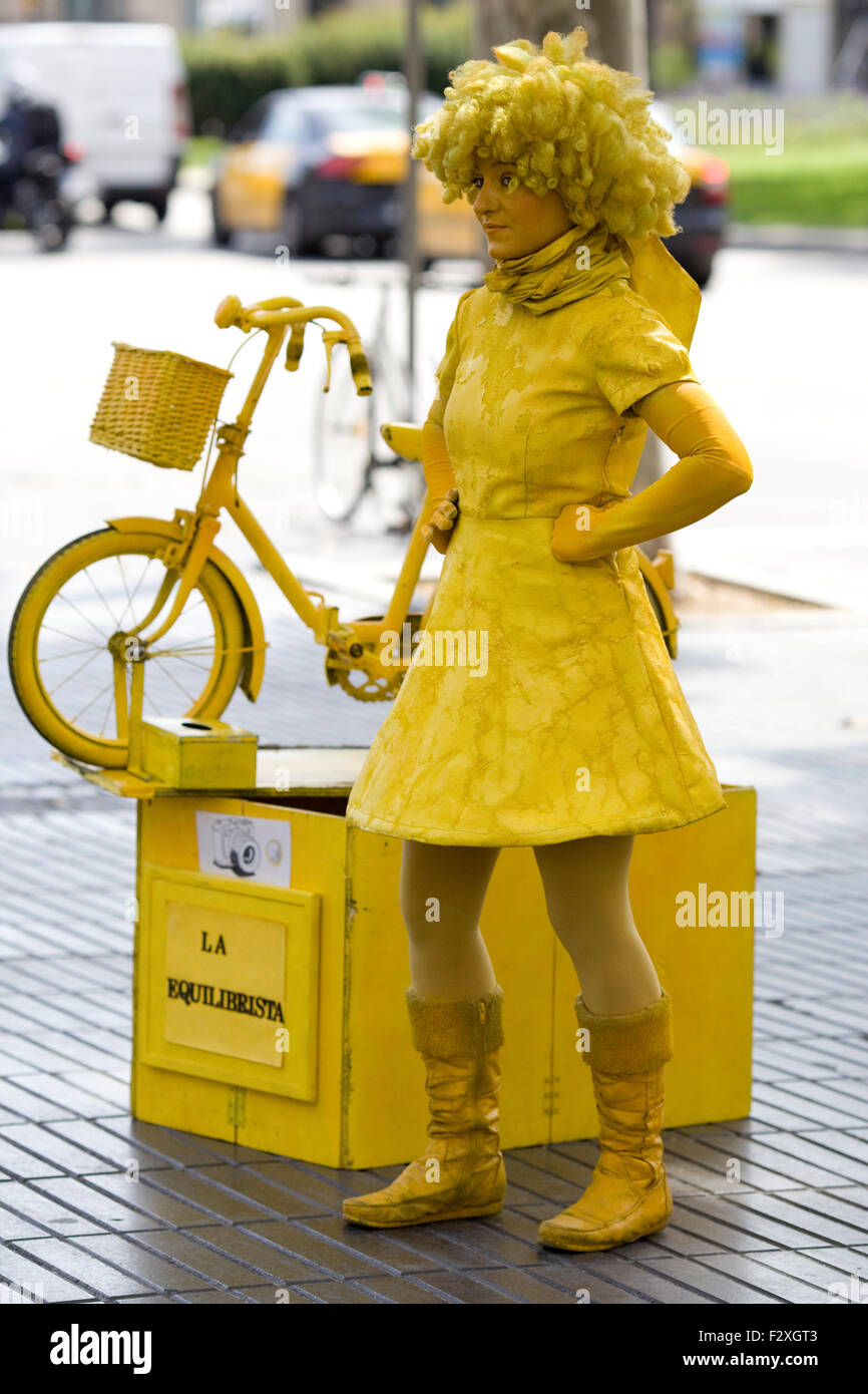 woman in yellow with a bicycle busking on the street of Barcelona Stock Photo