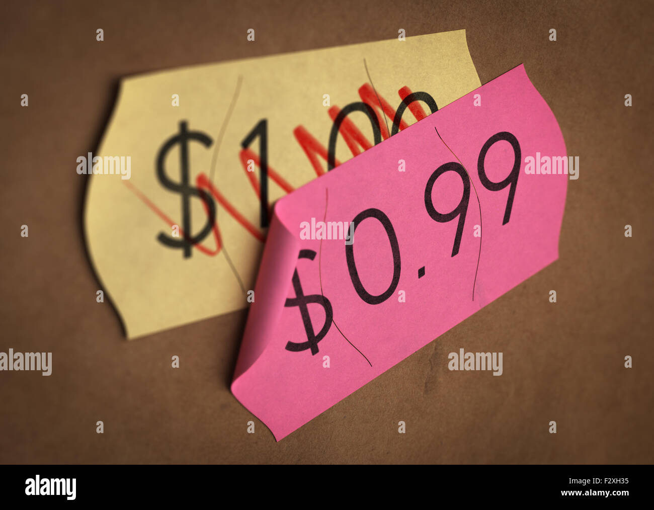 Psychological pricing printed on a pink label over a normal price. Concept image for illustration of prices psychological impact Stock Photo