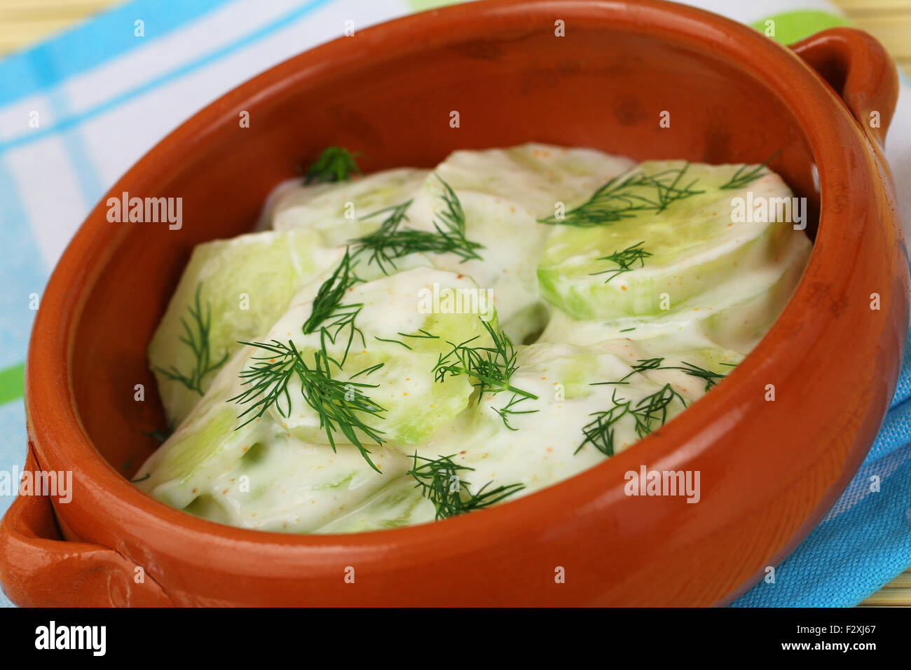 Cucumber salad with sour cream and fresh dill in clay bowl Stock Photo
