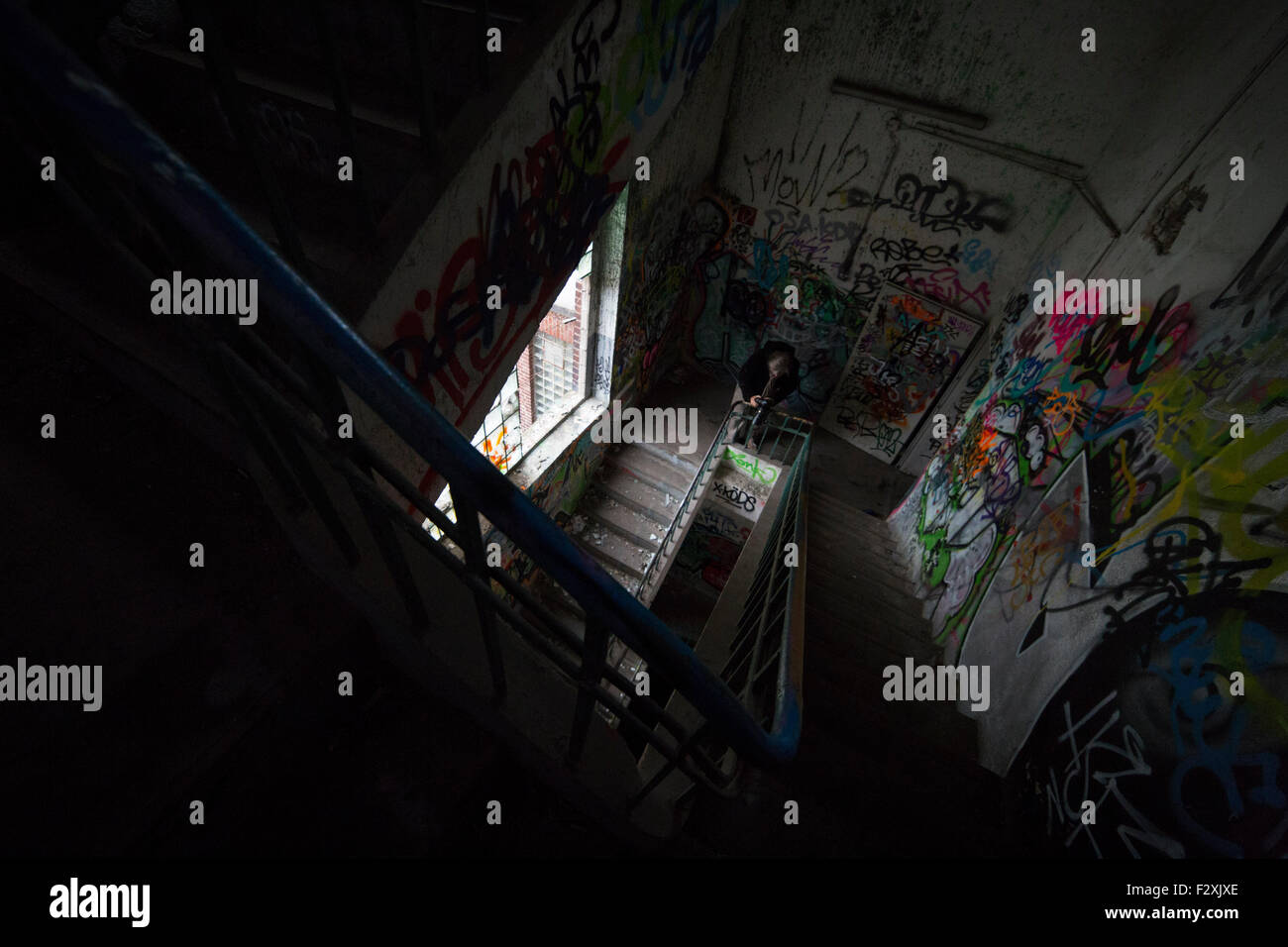 Hobby urbex photographer at work at the stairway of an abandoned factory in Germany Stock Photo