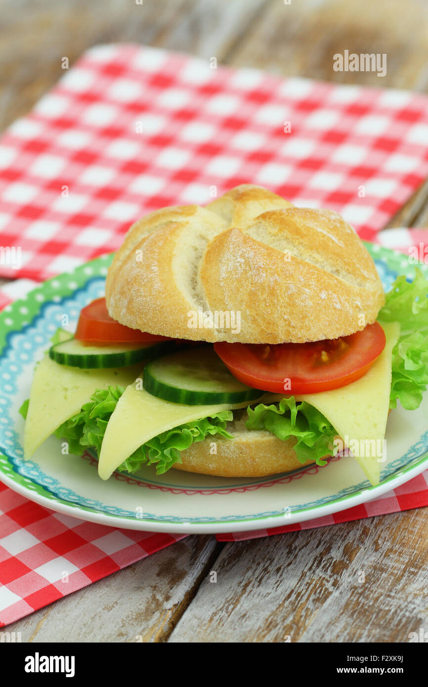 Cheese roll with lettuce, tomato and cucumber on plate on red and white checkered napkins Stock Photo