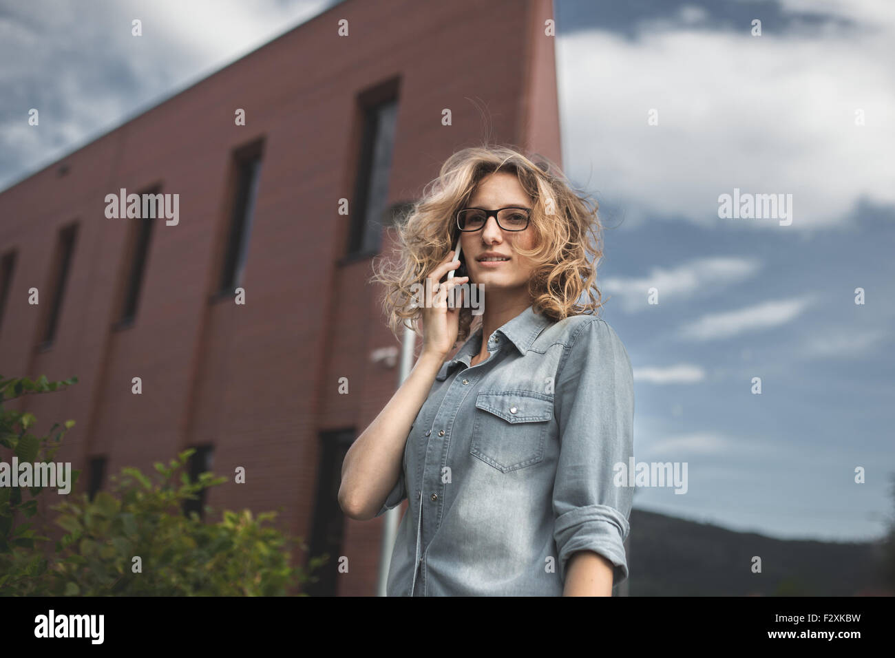 Young, confident, business woman in hurry.  Talking on smartphone while walking down the street. Portrait of businesswoman in ru Stock Photo