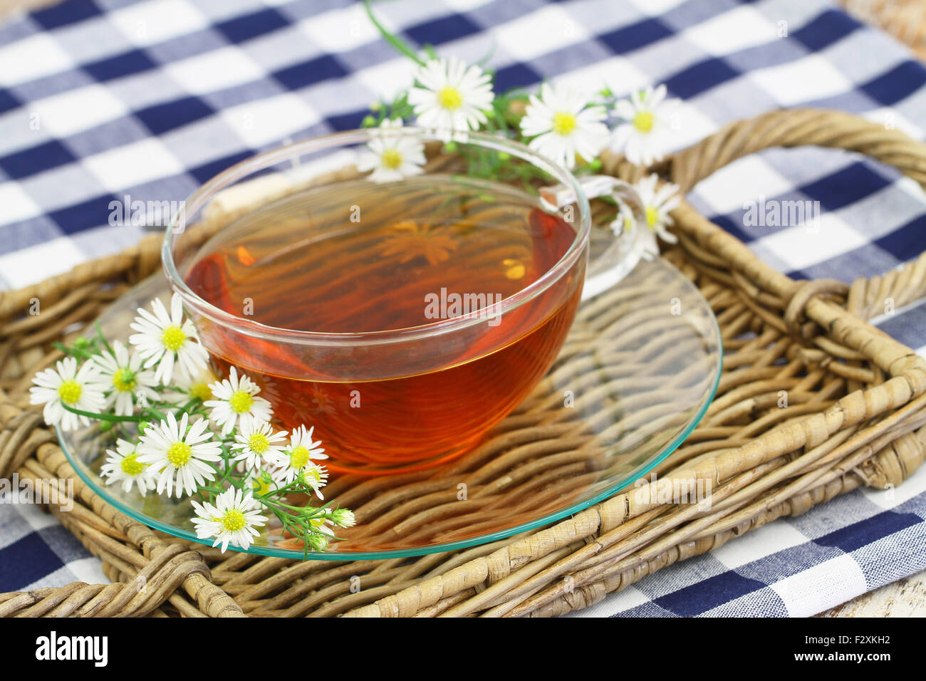Chamomile tea in transparent cup with fresh chamomile flowers on wicker ...